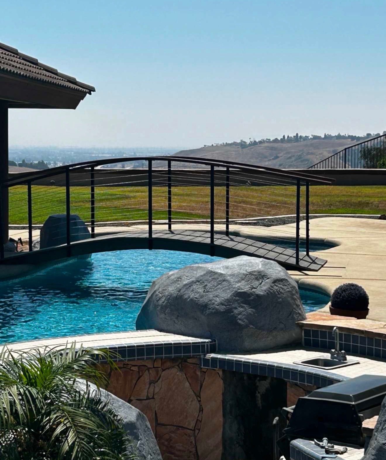 Poolside venue — black metal bridge with hillside view