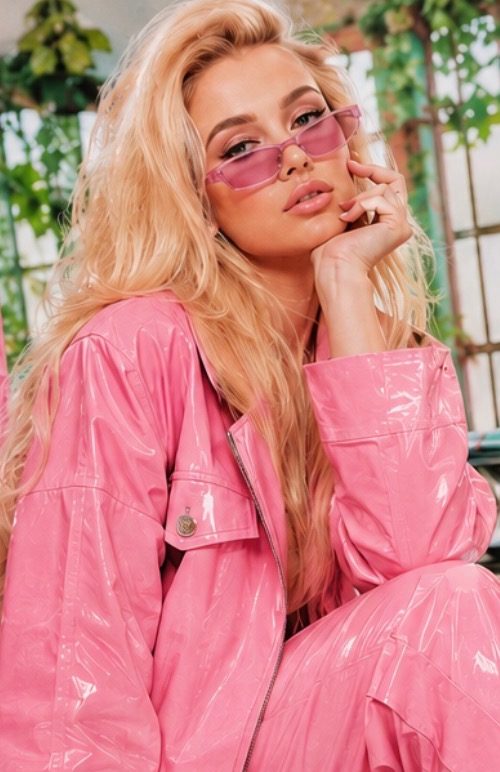 Model in a pink vinyl suit and pink-tinted sunglasses on one of the studio sets